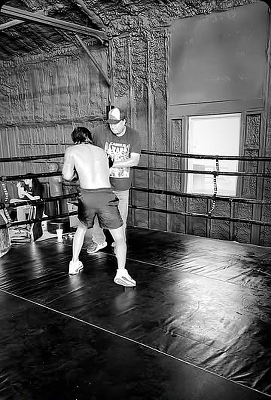 Boxer working the ring with a coach in black and white